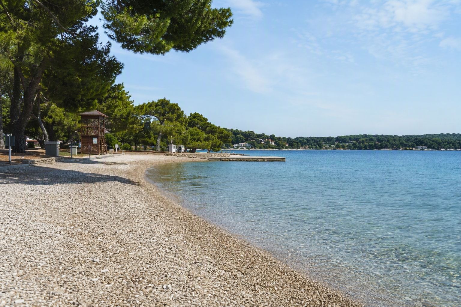 A city beach with pine trees and a lifeguard tower